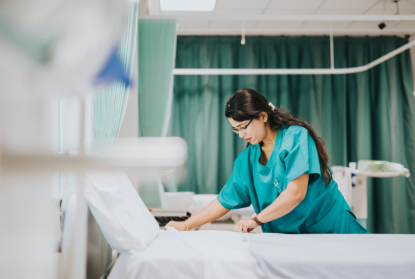A nurse making a hospital bed